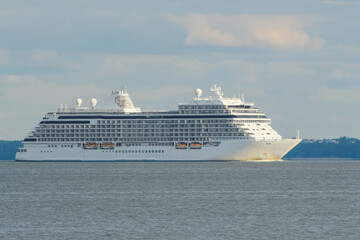 a multi-story, white cruise liner sailing on the sea