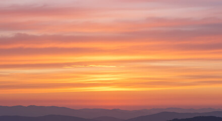 Fototapeta premium Panoramic Mountainscape at Dusk with Vibrant Orange and Pink Sky Tones
