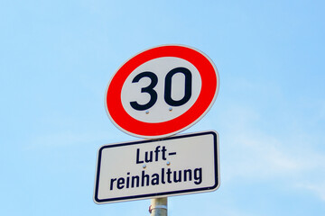 Tempolimit 30 zur Luftreinhaltung – Verkehrsschild in deutscher Stadt bei blauem Himmel	