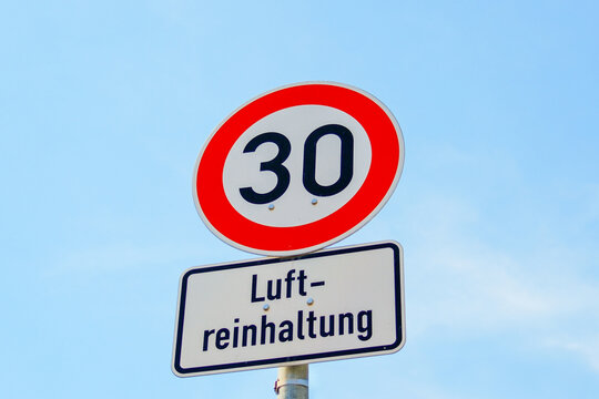 Tempolimit 30 zur Luftreinhaltung &ndash; Verkehrsschild in deutscher Stadt bei blauem Himmel	