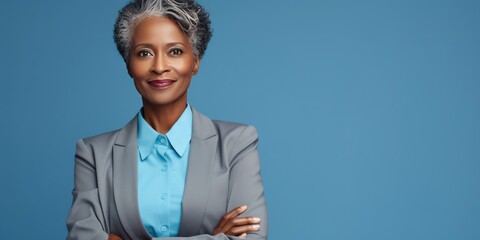 Confident smiling middle aged African American business woman ceo standing over blue background. Mature confident professional executive manager, proud lawyer, business leader in blue suit.