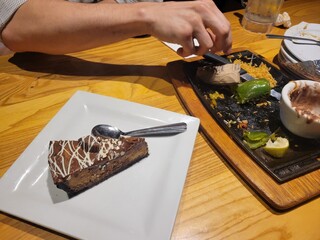 A person is carefully cutting a rich piece of chocolate cake on a plate