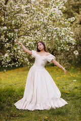 A girl in a dress and a blooming apple tree, taken at sunset