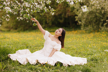 A girl in a dress and a blooming apple tree, taken at sunset