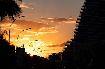 Sunset over Limassol city with modern buildings and construction crane silhouetted against vibrant evening sky