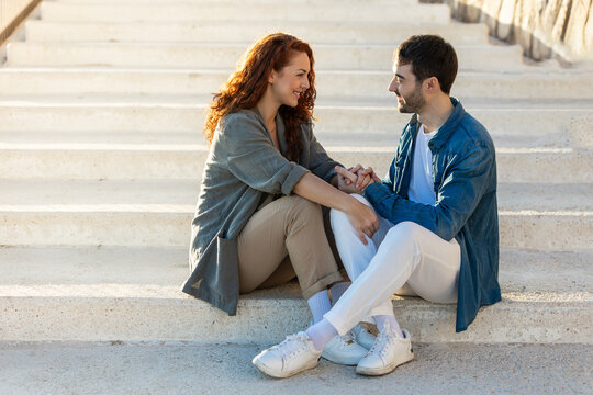 Smiling couple holding hands on sunny stone staircase. Lifestyle. Vacations.