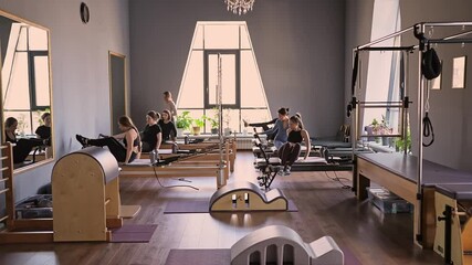 Woman training pilates on the reformer bed. Reformer pilates studio machine for fitness workouts in gym. Fit, healthy and strong authentical body. Fitness concept - Powered by Adobe