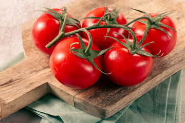 Fresh red tomatoes on a branch, on a wooden chopping board, close-up, no people,