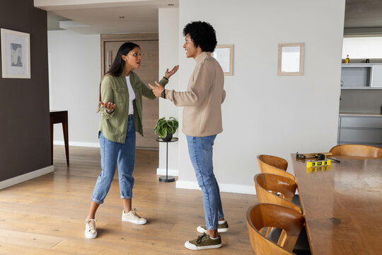 Talking couple standing in modern dining area, with dining table, spirit level and potted plant