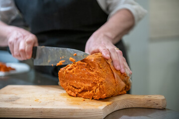 Close-up of hands cutting salami and prosciutto with a sharp knife for a charcuterie plate