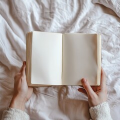Hand holding blank pages of a book on the bed 