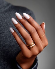 Woman Showcasing Elegant White Nails With Delicate Rings While Wearing Pearls and a Soft Shawl