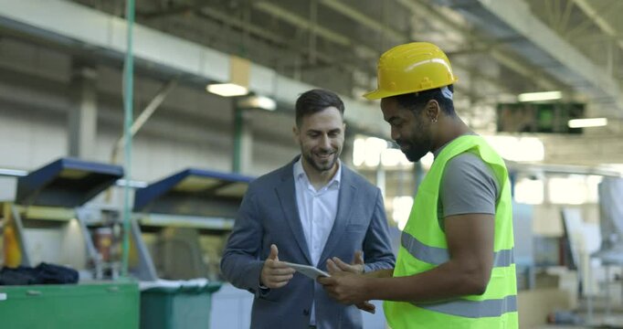 Businessman and Factory Worker Discuss Production on Tablet, Shake Hands, Showing Teamwork - Powered by Adobe