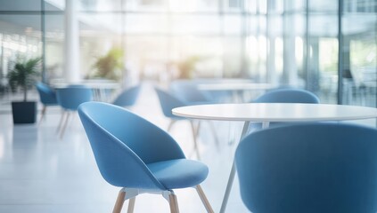 Modern, bright office breakroom with white tables and blue chairs