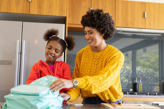 Packing mother and daughter together on marble countertop in kitchen, with mint green backpack