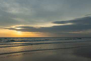 Beautiful sunrise over the ocean with birds soaring through the morning sky. The soft glow of dawn bathes the water and horizon in gentle pastel colors, creating a peaceful and atmospheric coastal sce
