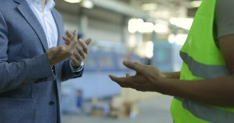 Businessman and Factory Worker Shake Hands on a Successful Deal in an Industrial Setting