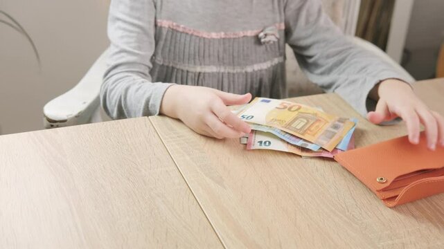 Child opening wallet full euro banknotes money on wooden table, finances, savings, and early financial awareness, Childhood curiosity, money management