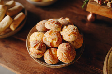 Ceramic bowl with golden cheese breads on a wooden surface. With a cracked crust and soft center, this classic from Minas Gerais represents authentic Brazilian comfort food.