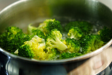Cooking fresh broccoli in a saucepan over medium heat during a sunny afternoon