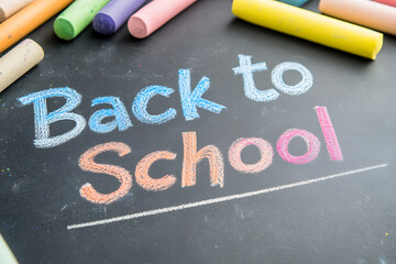 A chalkboard with colorful chalks announcing: "Back to School". A nostalgic reminder of education, learning, and a fresh start in an academic setting.