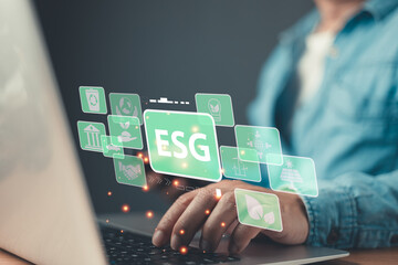 person types on a laptop with floating green icons representing ESG principles environmental, social, and governance highlighting sustainable practices, ethical standards, and responsible investment.