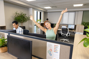 Diverse coworkers working at cubicle desks in modern office, with computer monitors and plants
