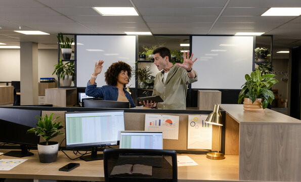 Discussing project data diverse coworkers standing at cubicle in office, with tablet and charts