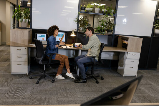 Celebrating success diverse coworkers exchanging high-fives in open-plan office, with screens
