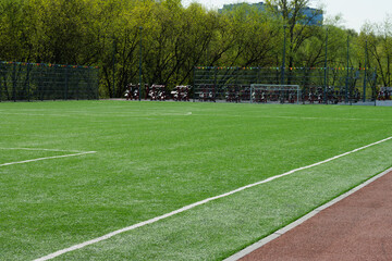 Soccer goal on big field with artificial green grass. Outdoor sports activities. Sports ground, field with artificial turf for playing soccer and other ball sport games. Summer season.