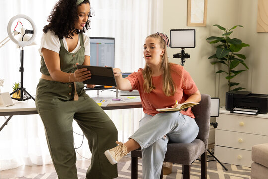 Collaborating diverse female coworkers planning project in home office, with tablet and ring light