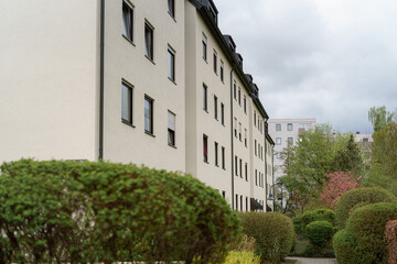 Fototapeta premium Modern residential building surrounded by greenery in a quiet urban neighborhood on an overcast day