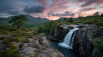 Fototapeta premium A scenic view of a waterfall cascading into a pool surrounded by lush greenery and mountains at dusk