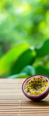 Close-up of a passion fruit on a bamboo mat. the passion fruit is cut in half, revealing its juicy red flesh and yellow seeds.