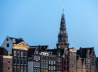 Obraz premium The old church tower with old town canal house during blue hour, Amsterdam, travel