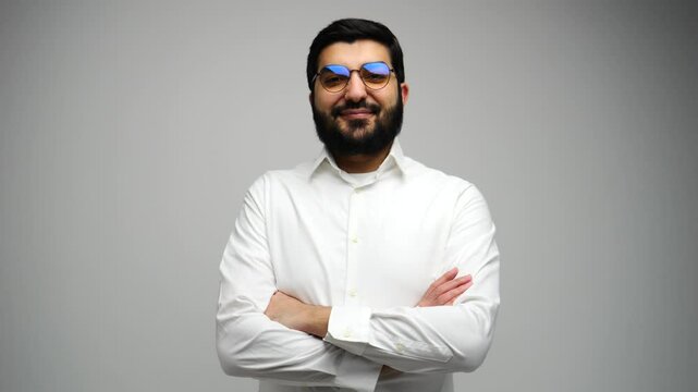 Confident man with beard standing against a neutral background, showcasing professionalism and charisma
