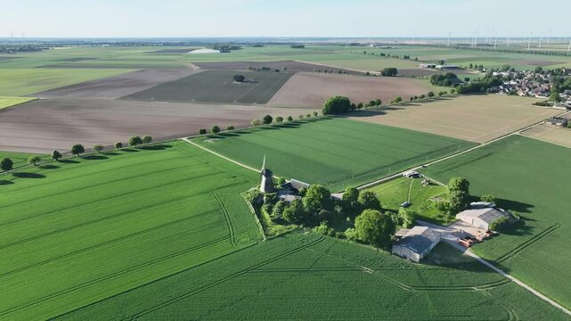 Luftbildvideosequenz der Grottenhertener Windm&uuml;hle bei Bedburg mit Kirchherten, Grottenherten und dem P&uuml;tzer Bach. Fr&uuml;hlingshafte Kulturlandschaft aus der Luft bei Sonne und leichter Bew&ouml;lkung