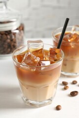 Tasty iced coffee and beans on white table, closeup