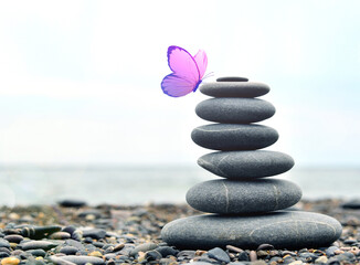 Stone tower. Natural pebble stone and butterfly on the beach. Mental health.