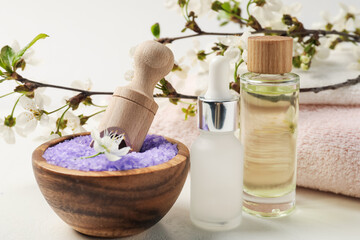 Composition with spa products and beautiful flowers on white textured table, closeup