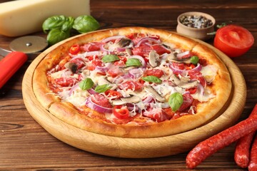 Tasty pizza with smoked sausages and ingredients on wooden table, closeup