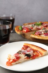 Slice of tasty pizza with thin smoked sausages served on grey table, closeup