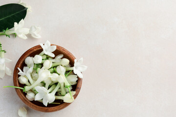 Bowl with jasmine flowers on beige table, flat lay. Space for text