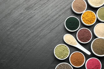 Different superfood powders on black table, flat lay. Space for text