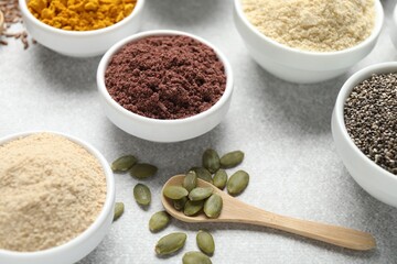 Different superfood powders on light grey table, closeup
