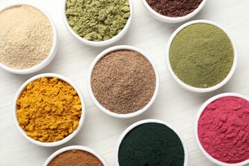 Different superfood powders on white wooden table, flat lay