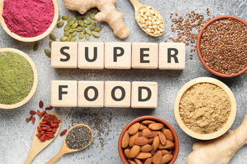Different superfoods and words made of cubes on grey textured table, flat lay