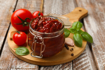 Tasty sun dried tomatoes, fresh vegetables and peppercorns on wooden table, closeup