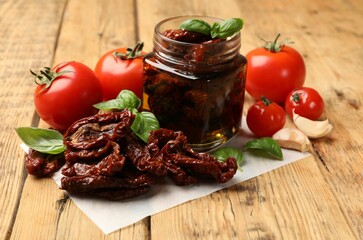 Tasty sun dried tomatoes and fresh vegetables on wooden table, closeup