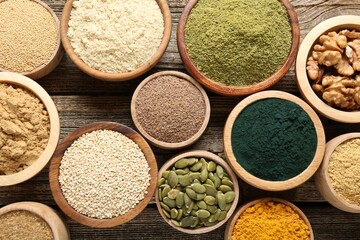 Different superfoods in bowls on wooden table, flat lay